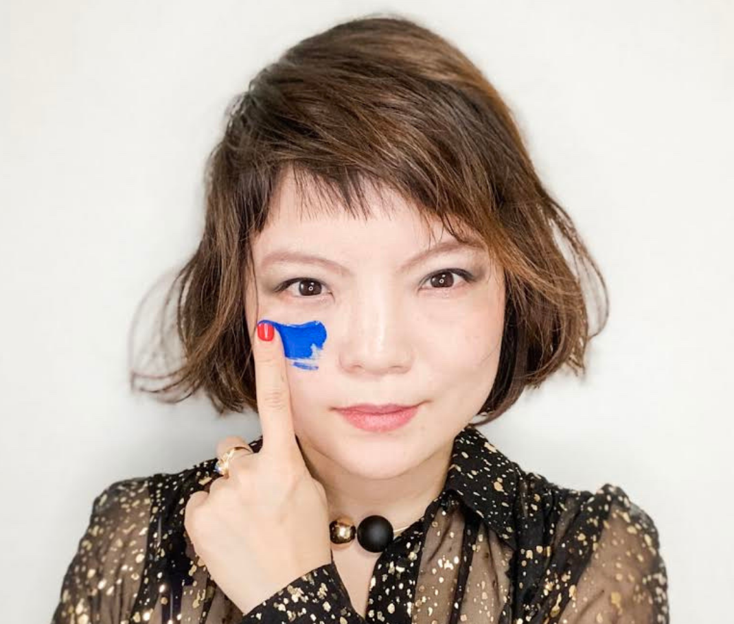 Simone Grace Seol — portrait, hand at cheek with blue paint mark.